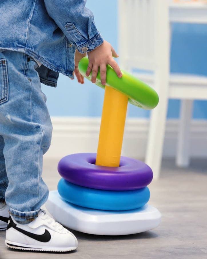 A child stacking colorful rings on a toy in the Sunny playroom