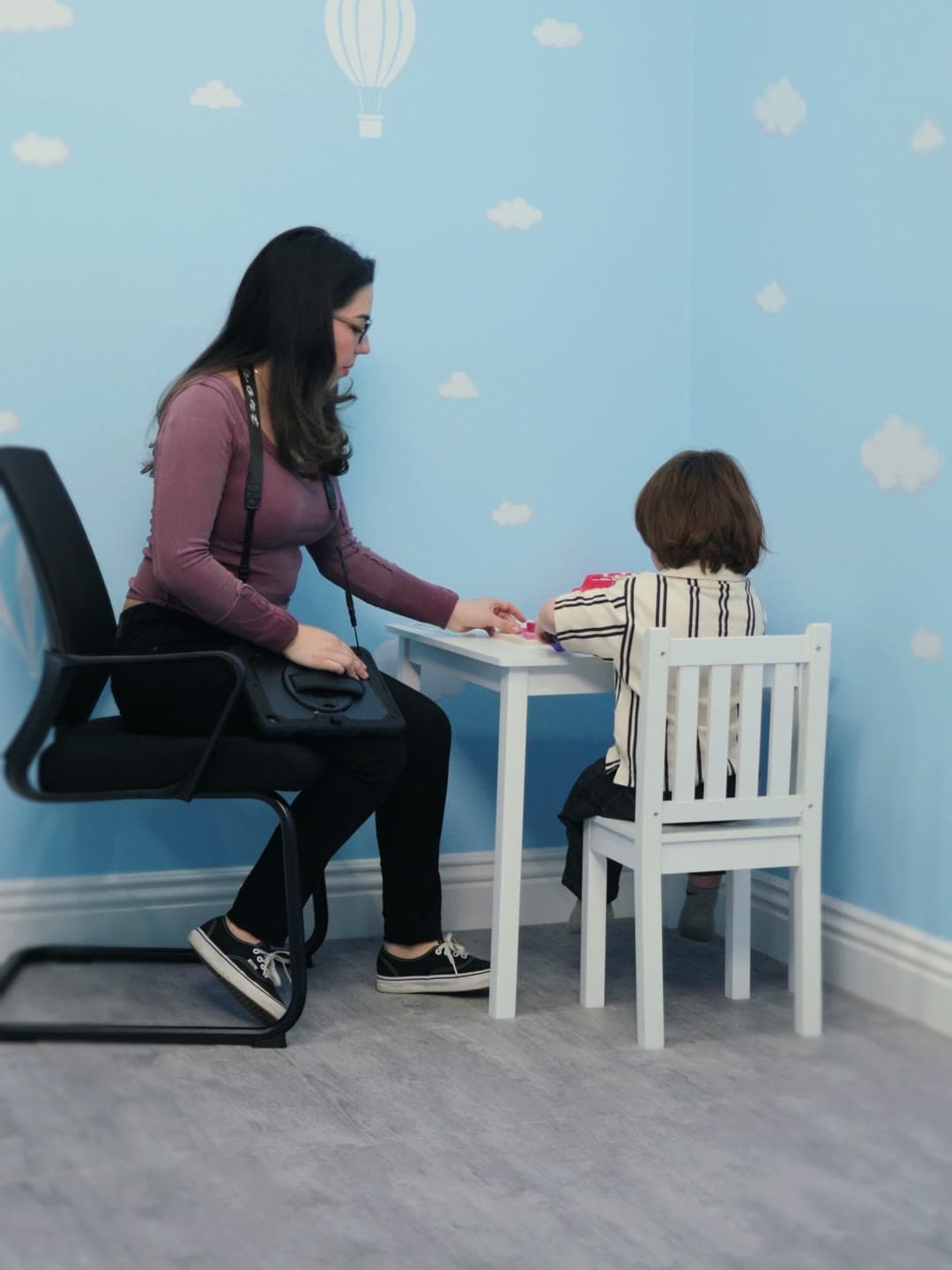 A BCBA sitting at a small table with a child during an assessment