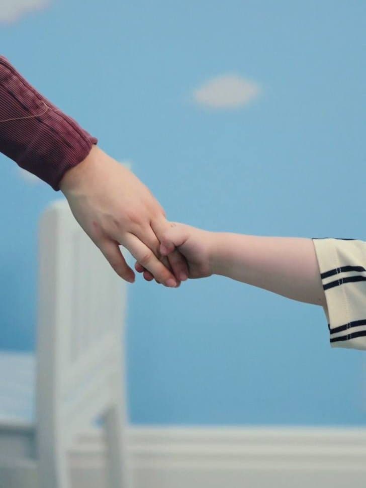 A therapist holding a child's hand in a Sunny therapy room